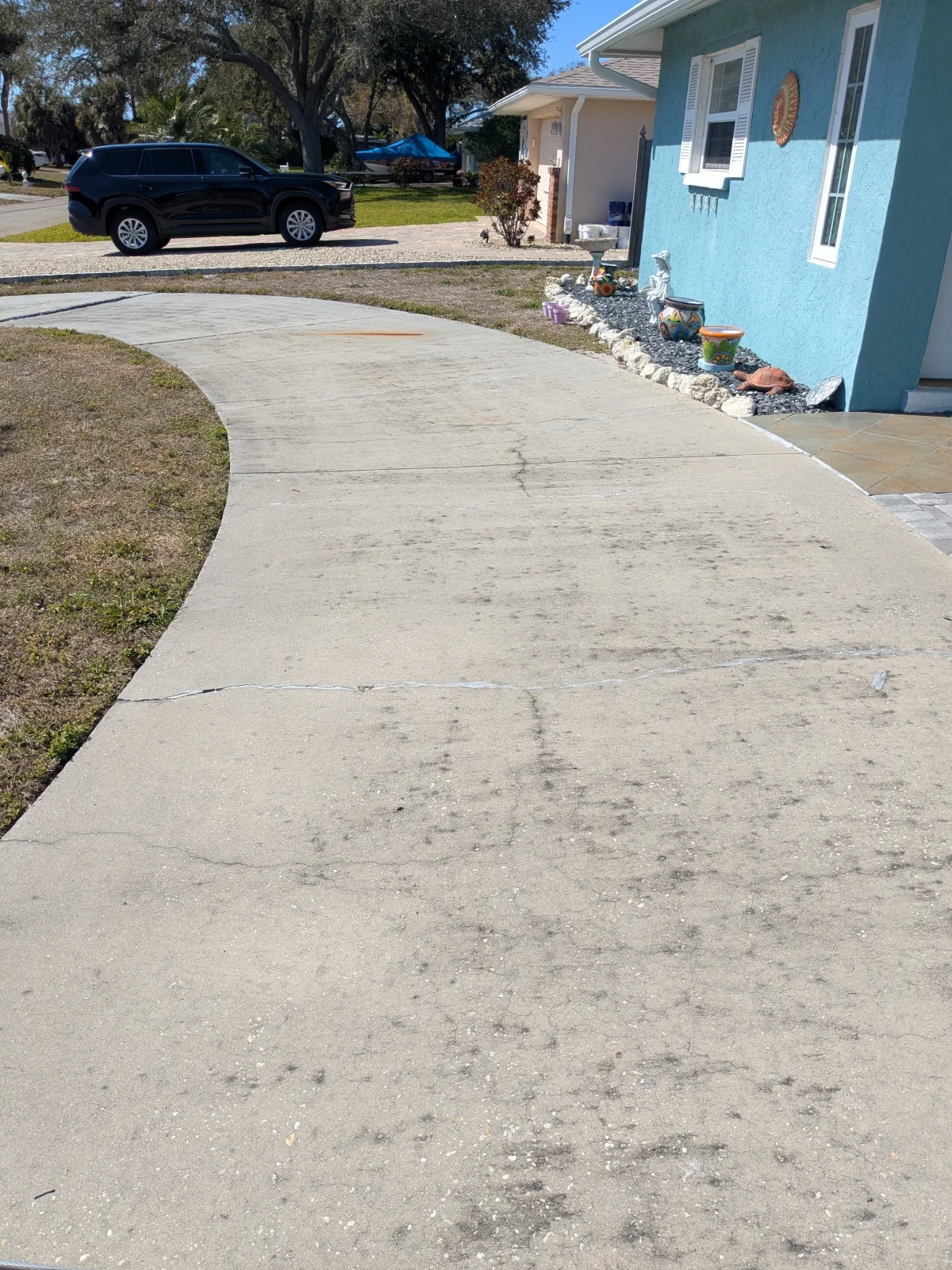 Curved concrete driveway near blue house