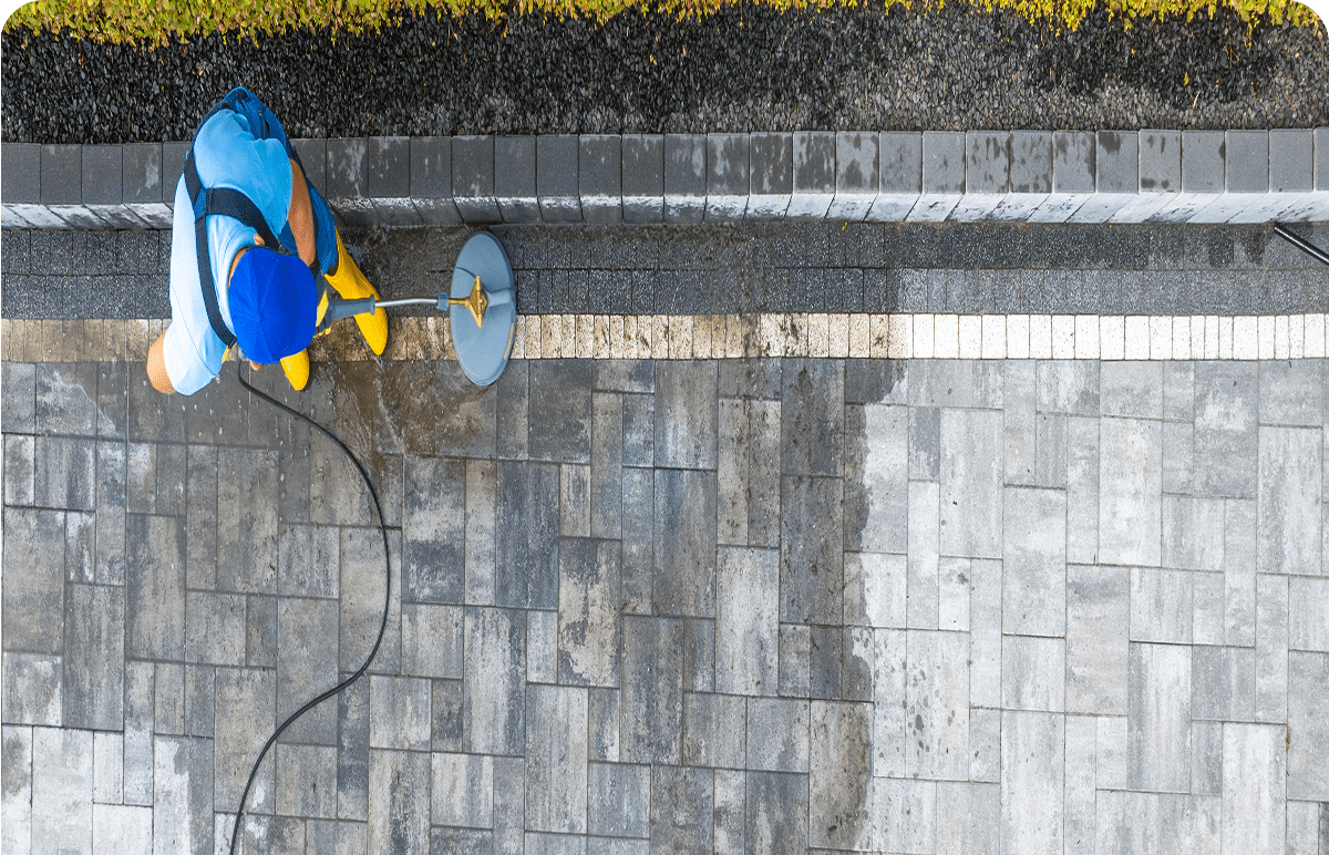 Man pressure washing stone walkway